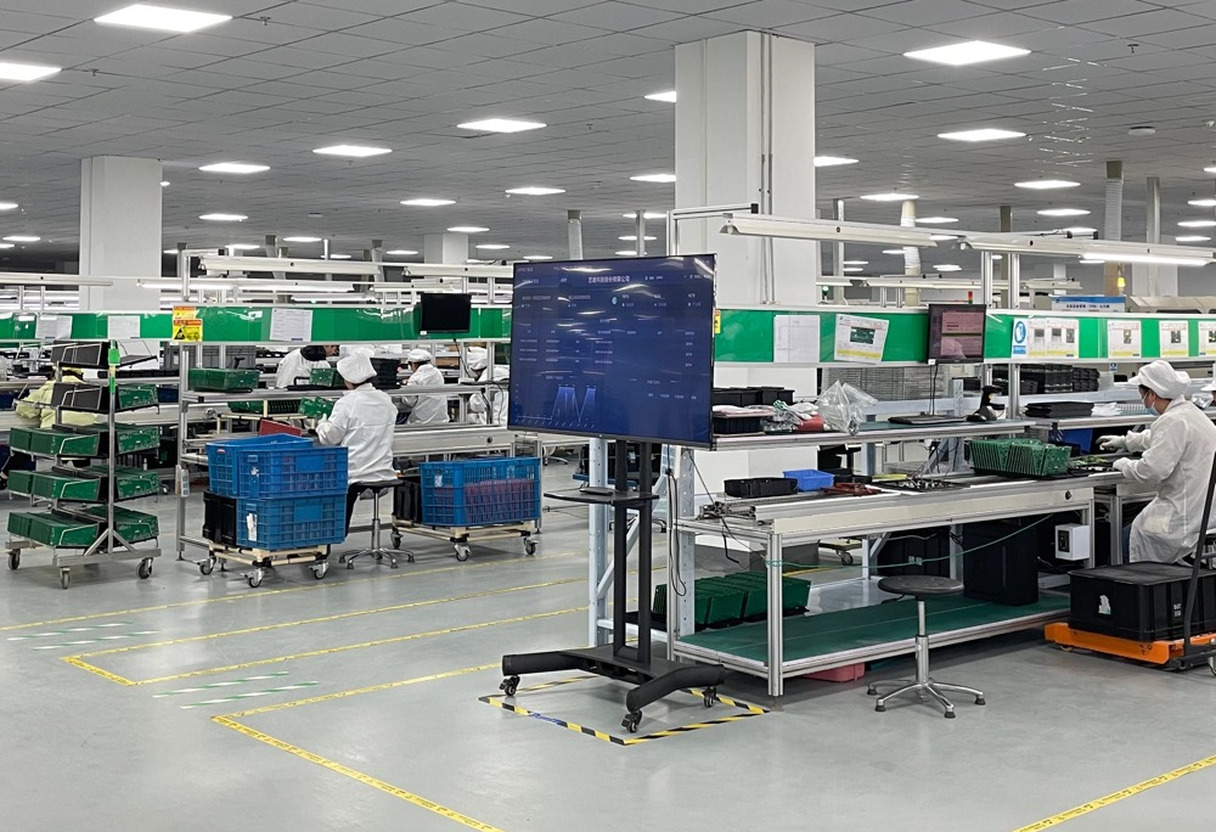 EV charger assembly and functional test stations with operators and test software displays on the Amprisen production line